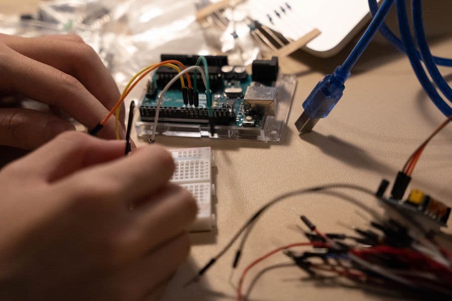 Hands connecting electronic components for IoT projects