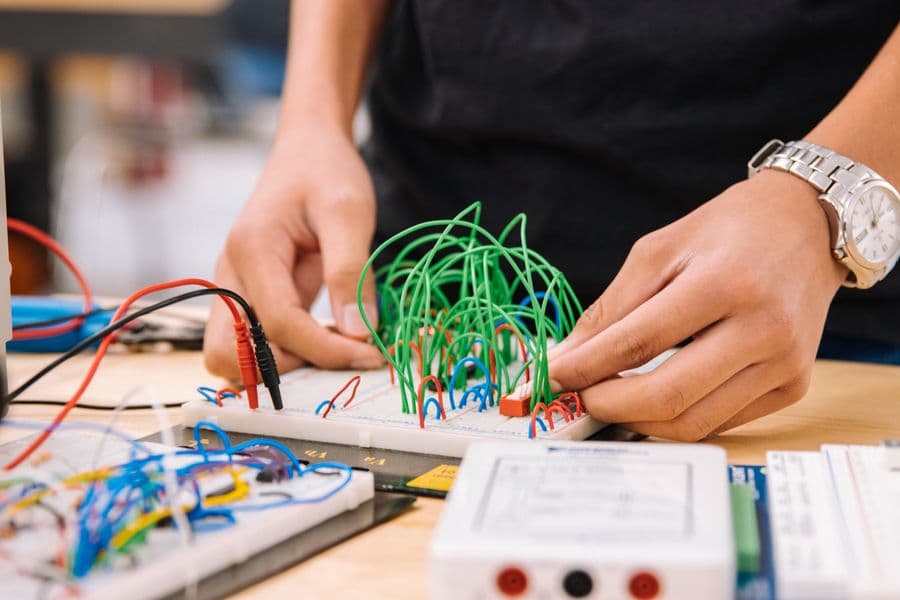 Hands working with electronics wires during a practical workshop